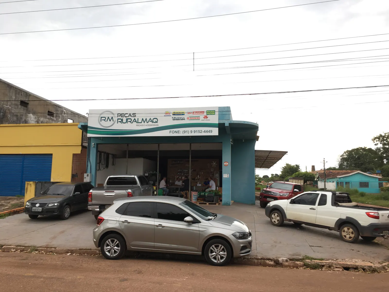 Loja de peças Ruralmaq vista da rua, com clientes sendo atendidos no balcão